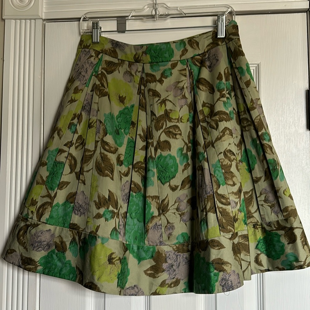 Odille floral printed skirt on olive green ground, pleaded front and back, sz 2